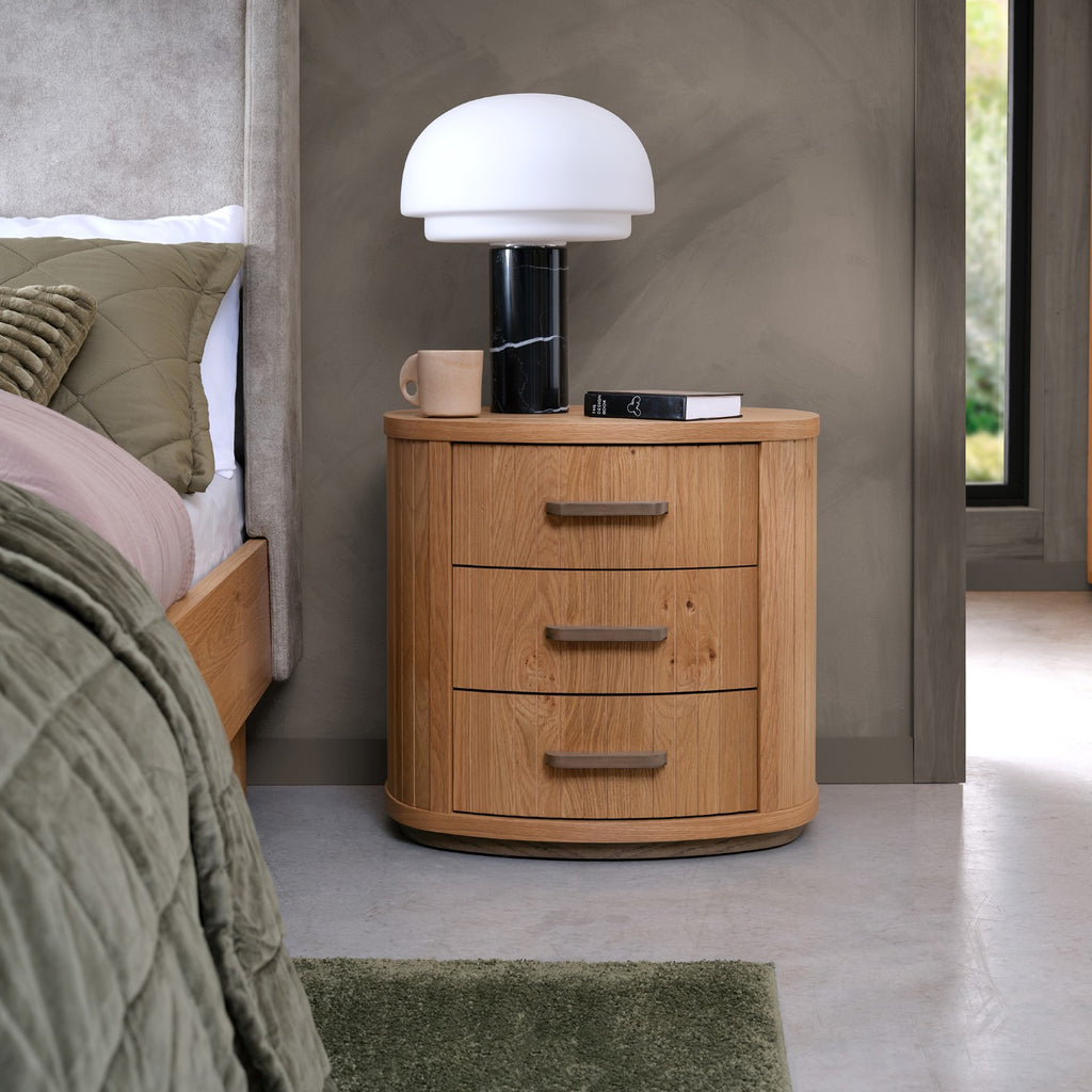 Weathered oak Bentley Designs bedside cabinet with three curved drawers, featuring a rustic, vintage-inspired bedside table design.
