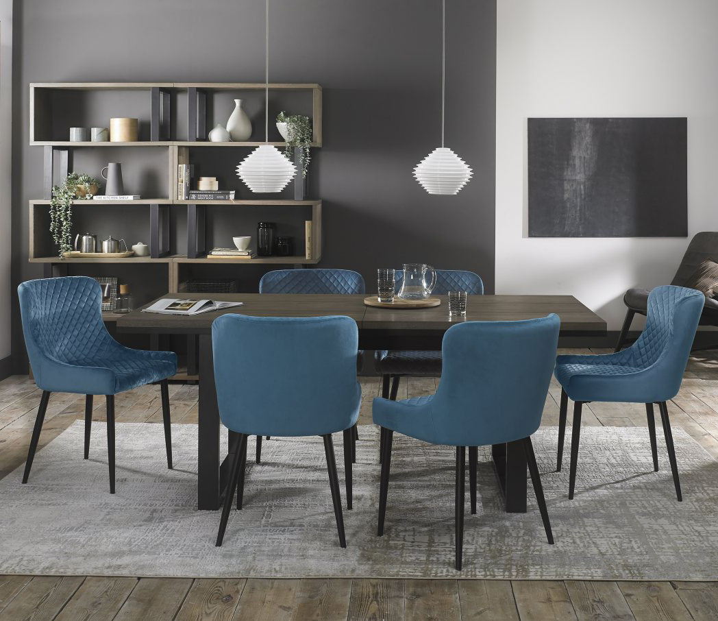Weathered oak extending dining table with six blue velvet Bentley Designs chairs in a stylish table and chair set.