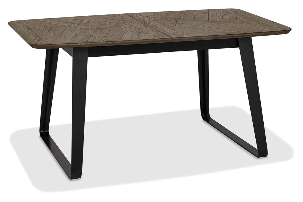 Weathered oak top extending dining table with black metal base by Bentley Designs, showing the table's surface and sturdy legs.