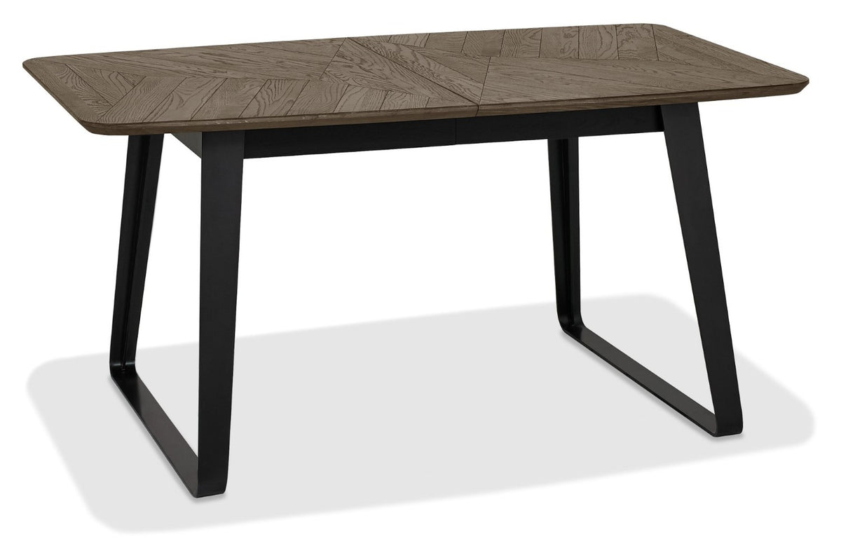 Weathered oak top extending dining table with black metal base by Bentley Designs, showing the table's surface and sturdy legs.