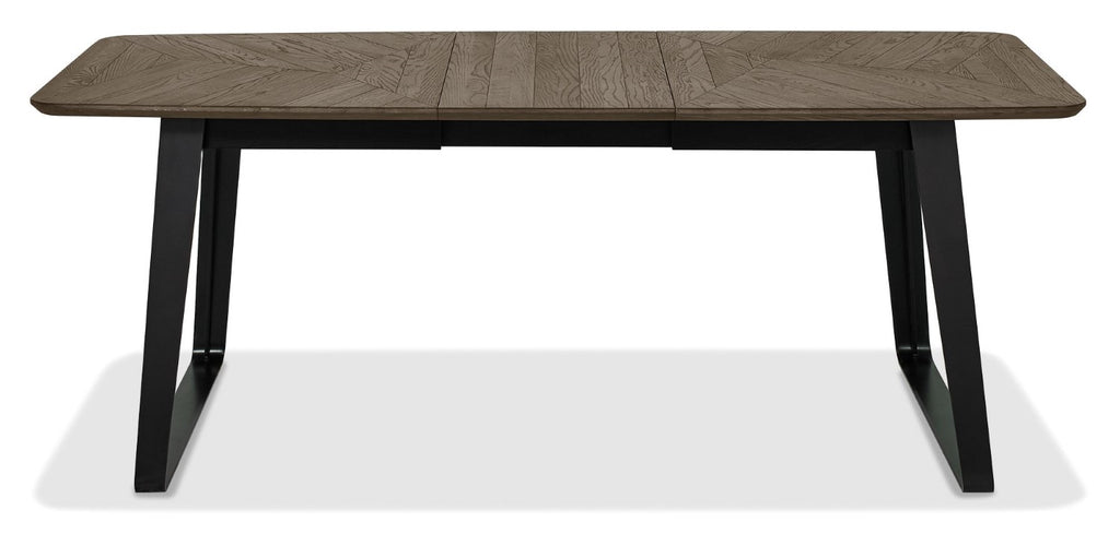 Weathered oak extending dining table with black metal base, designed by Bentley Designs, showing the table's wood grain and extendable feature.