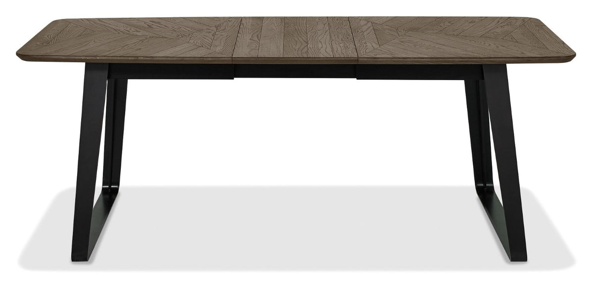 Weathered oak extending dining table with black metal base, designed by Bentley Designs, showing the table's wood grain and extendable feature.