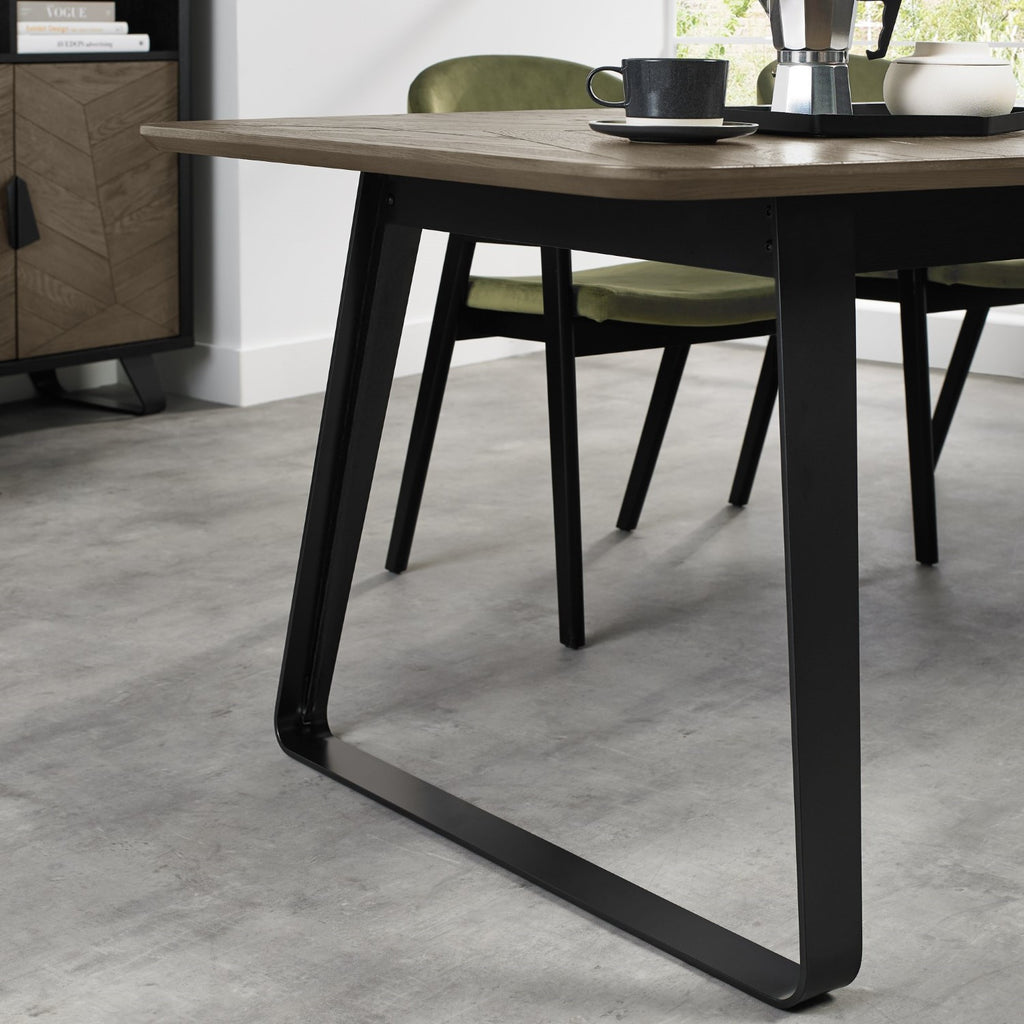 Weathered oak extending dining table with black metal base, designed by Bentley Designs, showing the table's rustic finish and extendable features.