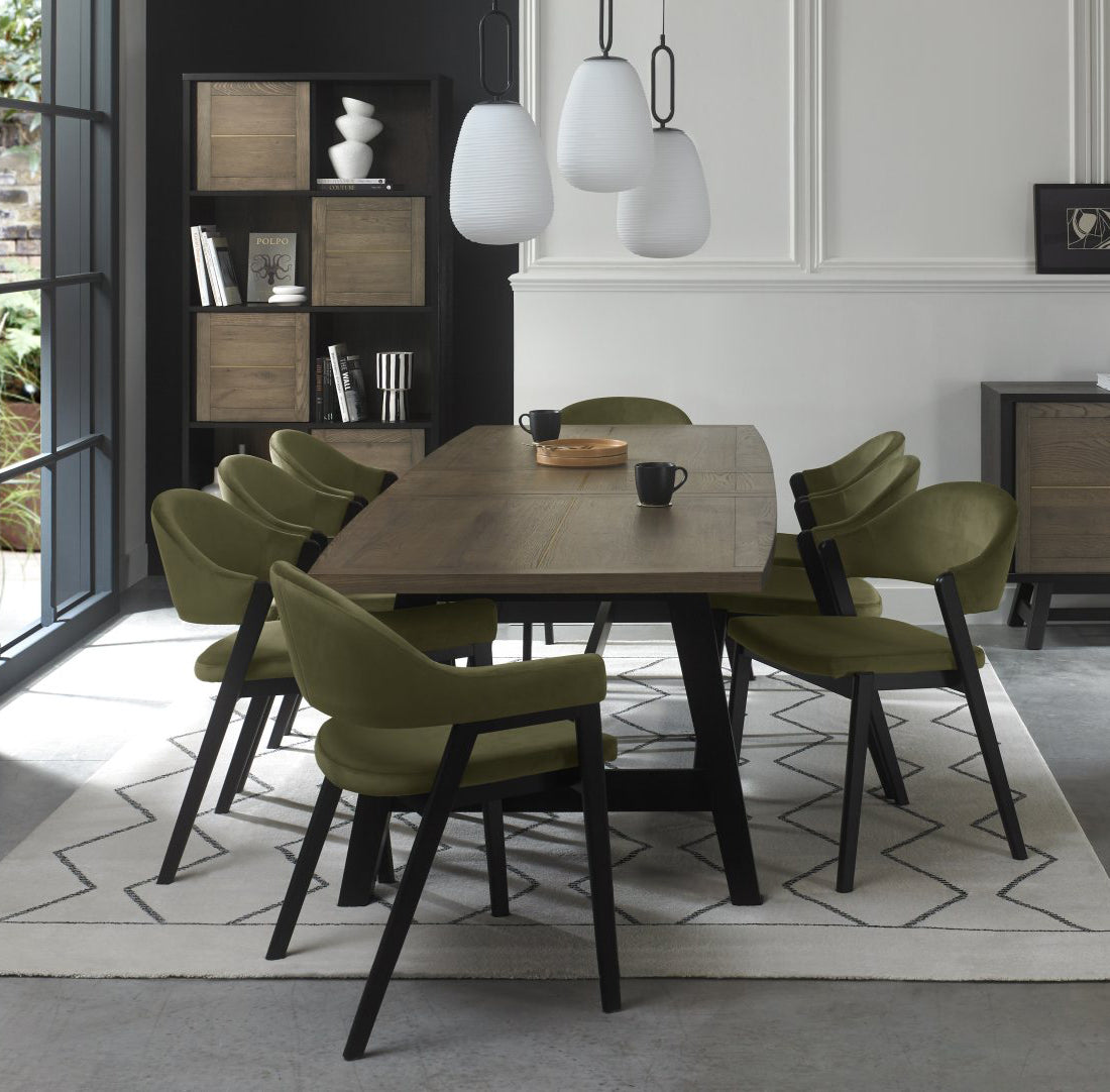Weathered oak dining table with eight green velvet chairs by Bentley Designs, showcasing a stylish table and chair set.