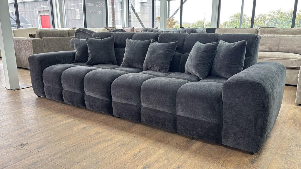 Large gray sectional sofa in a room with large windows.
