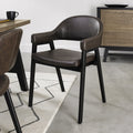 Vintage brown leather Bentley Designs dining arm chair with black legs, showing detailed upholstery and stylish wooden frame.
