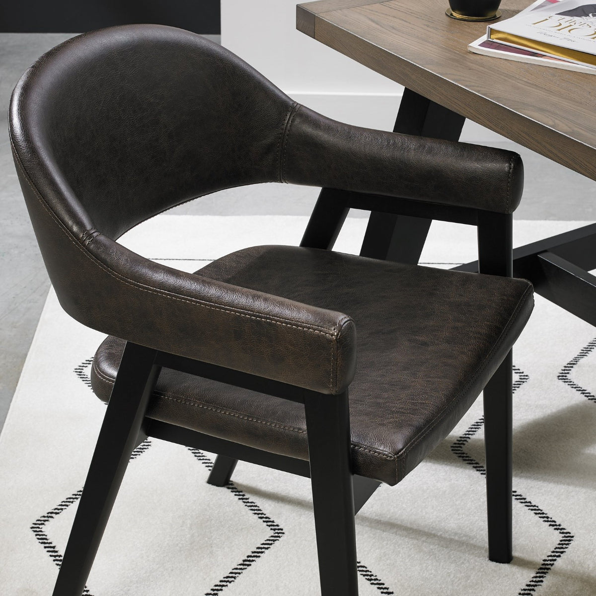Vintage brown leather Bentley Designs dining arm chair with black legs, featuring classic upholstery and elegant wooden details.