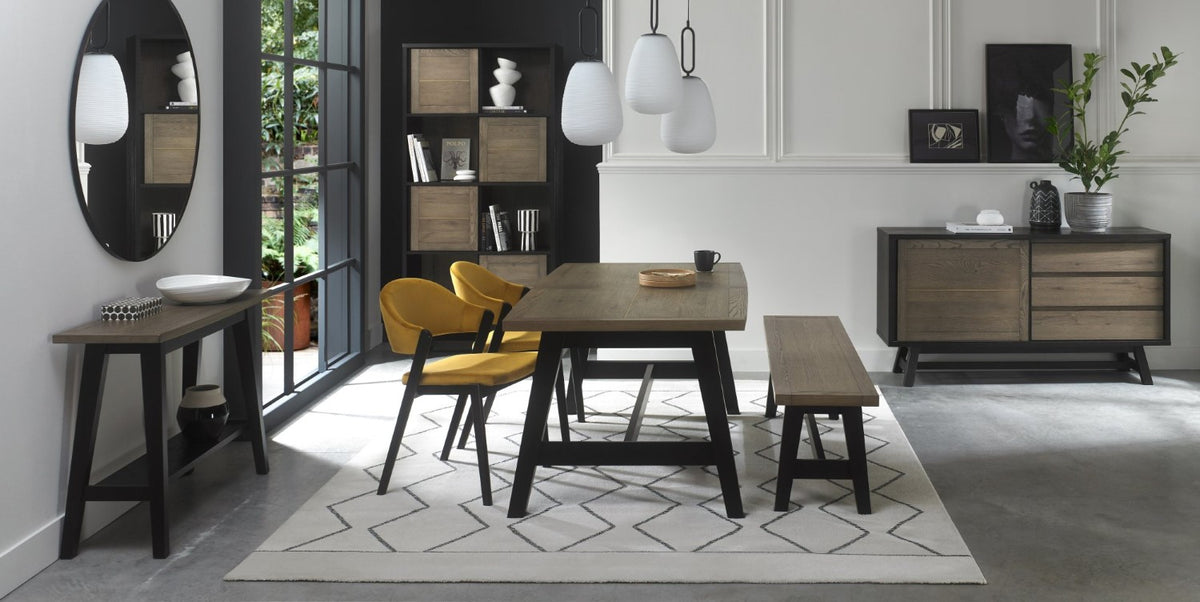 Weathered oak dining set by Bentley Designs with a table, two side chairs, and a bench, showcasing a rustic wood finish.