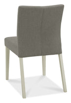 Bentley Designs washed oak dining table set with four grey fabric chairs, showcasing a modern, rustic dining room arrangement.