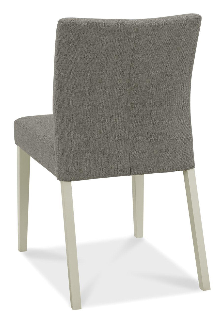 Bentley Designs washed oak dining table set with four grey fabric chairs, showcasing a modern, rustic dining room arrangement.
