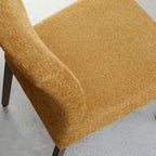 Pair of mustard yellow fabric dining chairs with dark oak legs by Bentley Designs, showing a close-up of the upholstered seats and wooden legs.