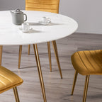 White marble glass round dining table with gold legs by Bentley Designs, showcasing a sleek modern design.