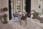 Modern dining room with round table, chairs, and decorative plants.